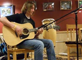 At a recent performance at Meadowlark Coffee House, Evan Potter plays an Epiphone guitar identical to the one donated by the BMF. Butch's conga drum is in the background. [Photo by Tom Ineck]