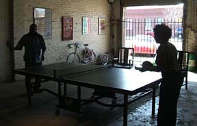 Grace Sankey-Berman (right) tries her hand at Ping Pong in Bill Brown's garage. [Photo by Bill Brown]