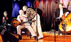 Ken Peplowski shows his affection for Bucky Pizzarelli as Dena DeRose and Tom Kennedy watch. [Photo by Fran Kaufman]